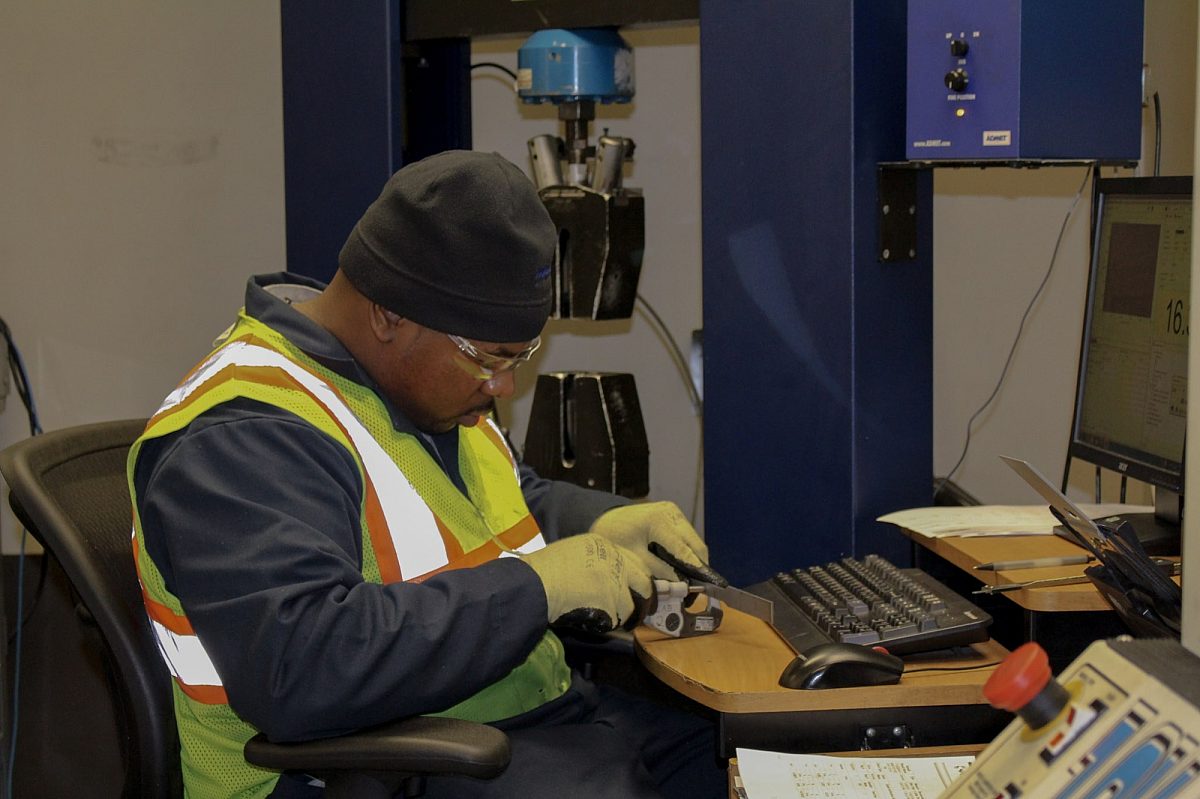 Close-up of a lab technician conducting tensile testing on steel.